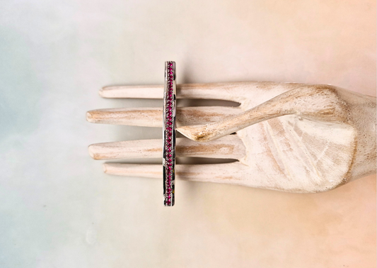 Ring with red gemstones on a wooden stand against a gradient background