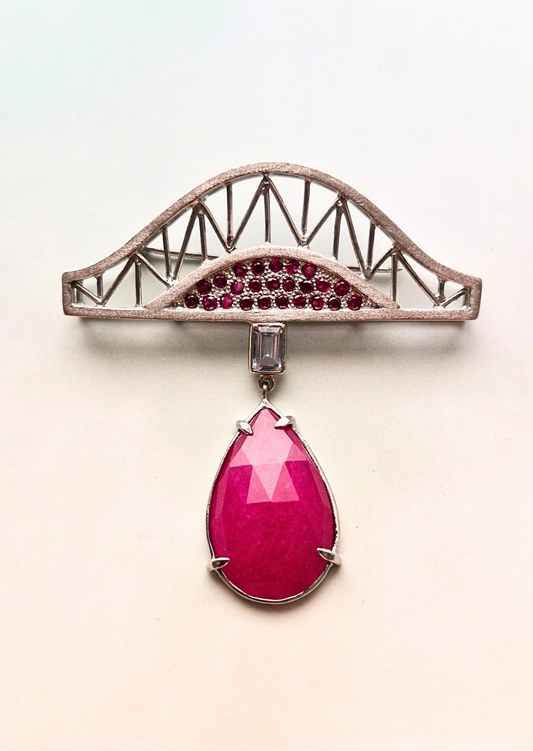 Jewelry piece with pink gemstone and red stones on a light background