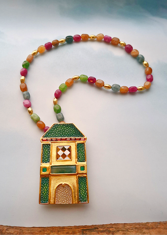 Colorful beaded necklace with a decorative gold and green pendant on a white background