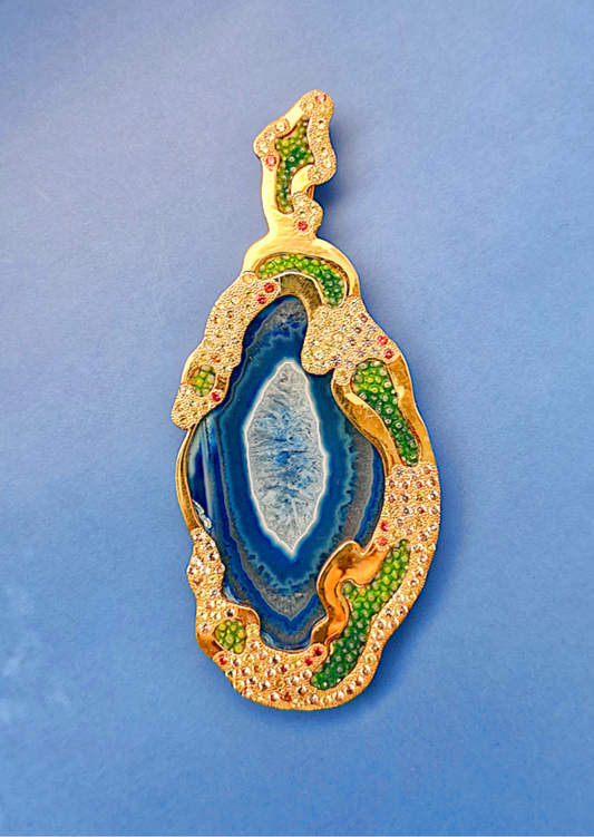 Decorative object with blue center and gold and green accents on a blue background