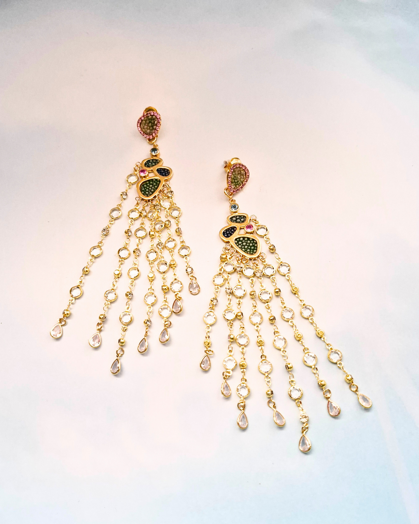 Gold jewelry with gemstones and stingray leather on a light blue background